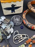 Close-up of jewelry including silver pendant, carved wooden bracelets, ceramic box, and shell necklace
