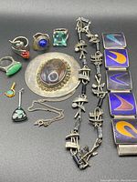 Assortment of rings, brooch, necklaces, bracelet and pin on black background