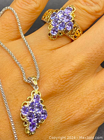 Close-up of ring and pendant worn on hand showing genuine natural tanzanite cluster stones with gold gilt overlay on sterling silver.