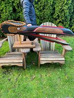 Full side profile of carved Raven mask on stand in outdoor setting