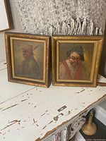 Overview of both framed portrait paintings on table