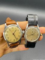 Pair of vintage men's mechanical wristwatches in hand, Zodiac with beige dial and brown strap, Favre-Leuba with cream patina dial and black strap