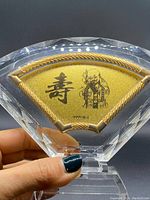 Close-up of front of gold plaque showing Chinese character, deity illustration, and purity marking.