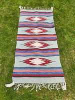 Full view of the vintage Navajo blanket laid flat showing pattern, color, and fringe ends.