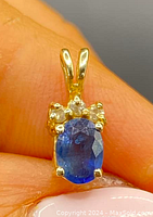 Front view of pendant showing oval blue sapphire flanked by three diamonds with gold bail