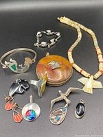 All jewelry pieces arranged on black background: bracelets, rings, necklaces, pendants and earrings