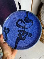 Top view showing the blue stoneware charger plate with black abstract design and speckled glaze.