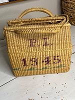 Front view of rectangular basket bag showing painted marking "E.L. 1945"