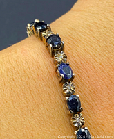 Bracelet on wrist, front-facing view showing alternating blue sapphires and diamonds.