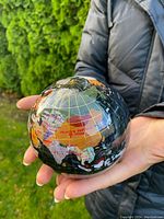 Photo of the gemstone globe held in hand showing Asia with detailed mosaics and country names