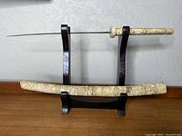 Full view of samurai cutter and scabbard on wooden display stand