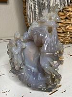 Front-left view showing overall form with carved figures and central stone mass.