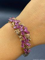 Bracelet worn on wrist showcasing ruby cluster design with gold gilt leaves.