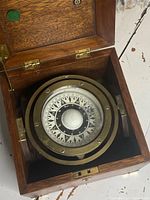Top view of the open wooden box revealing the brass mounted compass inside with detailed compass rose markings.