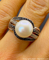 Close-up top view on finger showing central pearl and black diamond accents