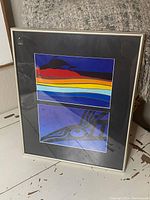 Framed artwork showing two prints stacked vertically inside a black mat and silver frame, placed on a white surface.