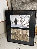 View of entire framed art piece showing two prints by Roy Vickers: top black bird on bare branches, bottom totem poles.