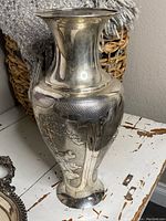 Front view of urn-shaped metal vase showing overall shape and textured shoulder band
