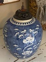 Front view of very large antique Chinese blue and white ginger jar with carved wood lid showing floral motifs on blue background.