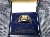 Front profile view of ring in blue velvet box showing prong-set solitaire stone centered on wide band