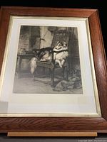 Framed etching artwork of a dog sitting on a chair inside a room, showing overall condition of the lot.