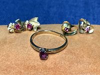 Ring and two pairs of earrings arranged on orange surface against blue background