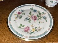 Single 10.75" dinner plate flat on surface, showing floral motif and gold rim