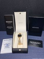 Watch, presentation box, warranty card, instruction booklet arranged on cloth background