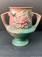 Front view of Roseville Waterlilly vase showing pink and green glaze with detailed waterlilly flower and leaves relief on rounded body and two handles.