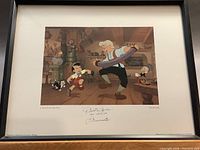 Framed color print depicting scene from Pinocchio with Pinocchio, Geppetto and Jiminy Cricket