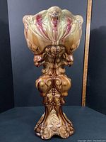 Front view of large Majolica style jardiniere with ornate sculptural details in earth tone glaze.