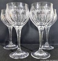Four vintage Peill & Putzlar crystal goblets with etched Diana floral pattern displayed on black foam background.