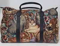 Full view of tapestry travel bag showing multiple cats in various colors, leather handles, and straps