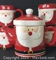 Front view of Santa Claus ceramic teapot with lid and four matching mugs arranged behind it