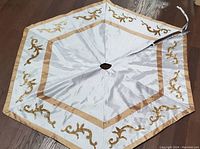 Full view of reversible Christmas tree skirt laid flat, showing white fabric with beige and gold ornamental borders.