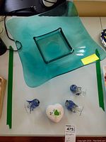 Photo of large blue glass serving tray with curved edges, three blue and clear glass birds, and heart-shaped Belleek ceramic jar with shamrocks.