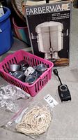 Photo of boxed Farberware stainless steel 18-55 cup coffee urn and accessories including chafing fuel cans in pink basket, tablecloth clips, electric timer, and string.