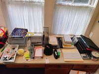 Photo showing wide variety of office supplies on desk including organizers, calculators, tape, keyboard, and various paper supplies