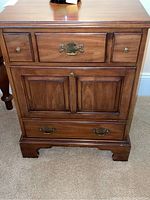 Front view of the Virginia Galleries wood nightstand showing drawer and door layout with brass pulls.