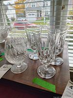 Group of five assorted Waterford crystal glasses on a wooden surface, showing different cut styles and shapes.