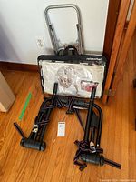 Photo showing carry bag in plastic cover with printed instructions, snap rack frame with striped straps, and luggage trolley with metal frame and black base.