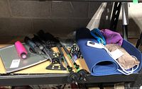Photo showing the full lot including scales, umbrellas, walking sticks, yoga mat, towels and other accessories on a shelf.