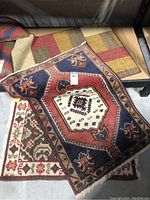 Top view of 3 mats stacked showing Persian navy/orange mat and brown/green block pattern mat with rubber-backed mat on bottom