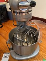 Front view of mixer head with KitchenAid logo and metal bowl in place. Splash guard attached.