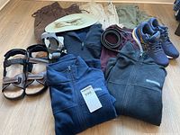 Lot arranged on floor showing all pants, jackets, footwear and accessories in view.