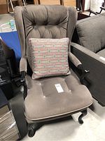 Front left angle view of the grey tufted occasional wing back chair with throw cushion, showing the overall condition and design.