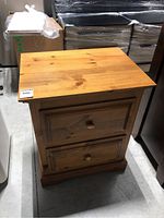 Full view of pine nightstand showing natural wood grain and two drawers closed.