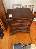 Front view of cherry wood bedside table with 3 drawers showing overall condition and design.