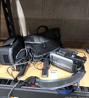 Sony Handycam video camera with charger, batteries, cases on shelf.