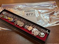 Overview of sterling link bracelet with 12 charms on red felt